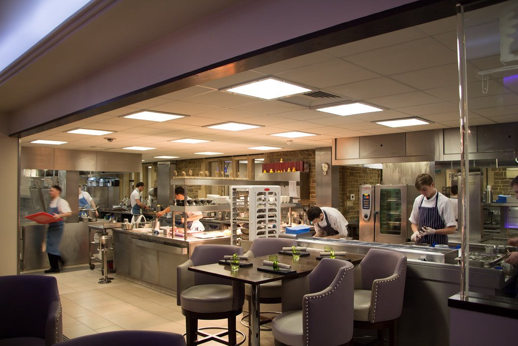 Professional restaurant open kitchen with chefs working at stainless steel stations